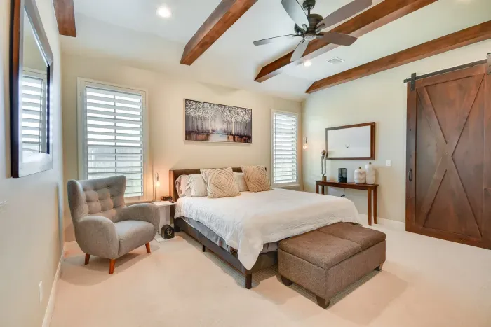 Primary bedroom with exposed beams and barn door accents.