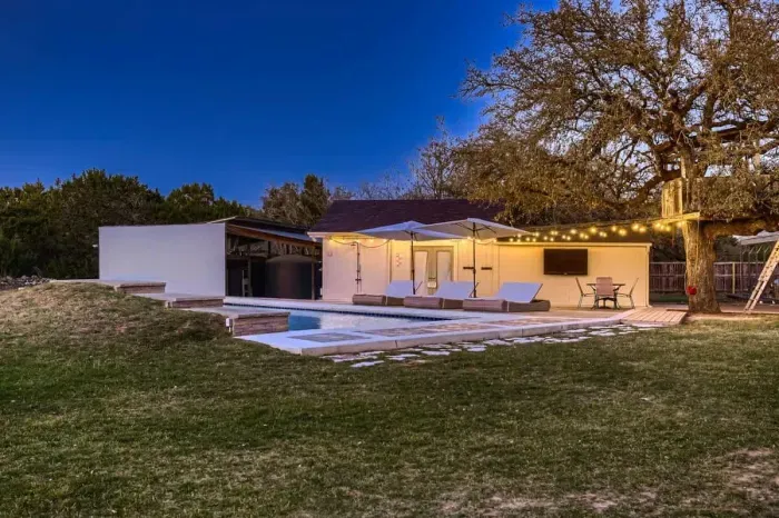 Modern poolside lounge with string lights, an inviting space to relax day or night.  Just let us know if/when you want to use it!