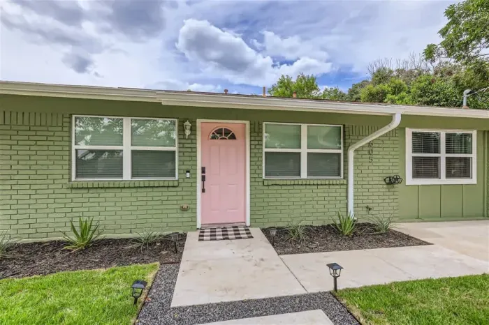 Welcoming front exterior with charming pink door, shaded entry, and modern curb appeal
