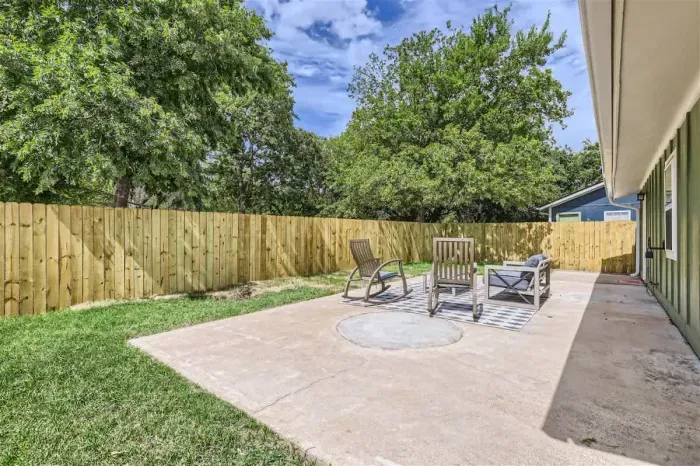 Spacious backyard with outdoor dining set, green lawn, and room to relax under the open sky.