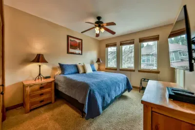 Inviting bedroom equipped with a TV and large windows, allowing for plenty of natural light and entertainment options. This bright and airy space offers a comfortable retreat for relaxation, combining modern amenities with a refreshing atmosphere.