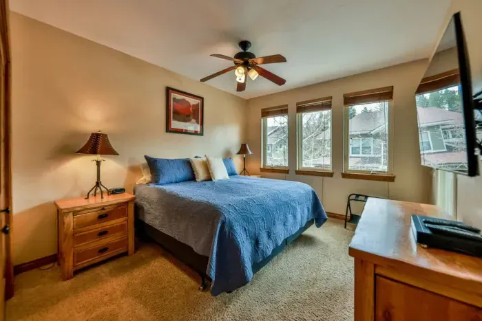 Inviting bedroom equipped with a TV and large windows, allowing for plenty of natural light and entertainment options. This bright and airy space offers a comfortable retreat for relaxation, combining modern amenities with a refreshing atmosphere.