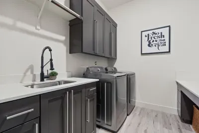 Laundry Room with sink, full-size washer & dryer, and workspace.