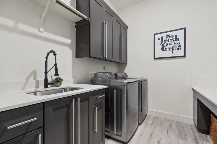 Laundry Room with sink, full-size washer & dryer, and workspace.