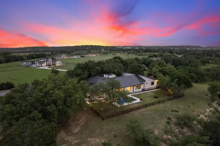 Modern meets Hill Country with a mix of clean lines and traditional limestone...with soaring oak trees throughout the property.  Serene and picturesque setting with the San Gabriel River and Goodwater hiking trail behind the property