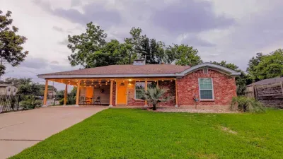 Full exterior view highlighting the spacious lawn and classic brick front