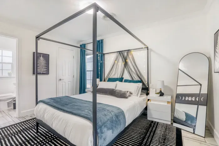 Stylish primary bedroom with a modern canopy bed, soft lighting, and cozy layered bedding