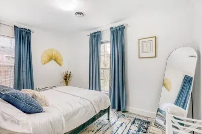 Cozy second bedroom with a full-length mirror and stylish modern accents.