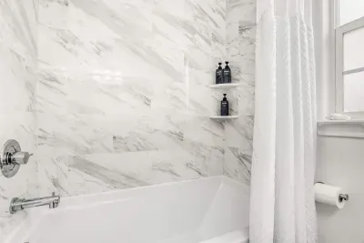 Bright, marble-tiled shower with a deep soaking tub and sleek chrome fixtures offering a clean, calming, and designed for a refreshing start or slow unwind.
