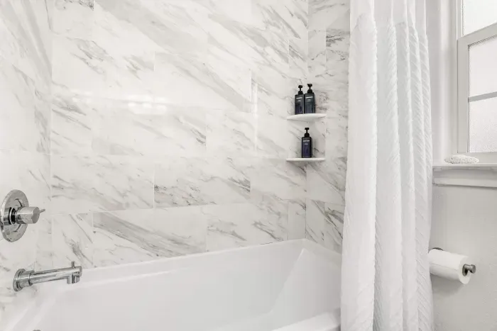 Bright, marble-tiled shower with a deep soaking tub and sleek chrome fixtures offering a clean, calming, and designed for a refreshing start or slow unwind.