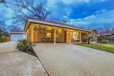 Charming Austin bungalow with a covered porch, café seating, and warm evening lighting.