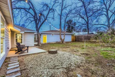 Relax in the private backyard beneath string lights with Adirondack seating and mature shade trees.