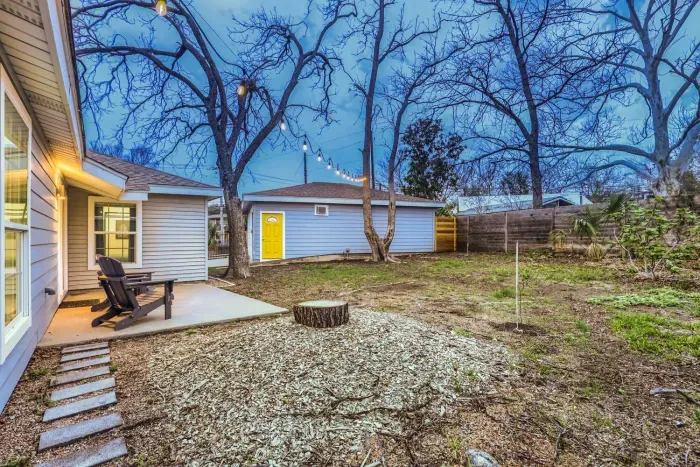 Relax in the private backyard beneath string lights with Adirondack seating and mature shade trees.