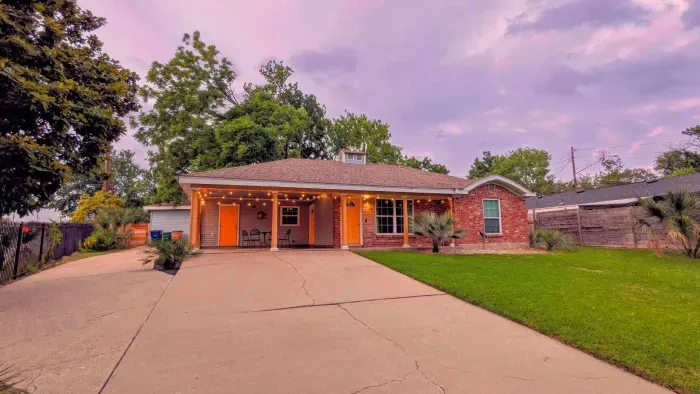 Front view of the home with inviting porch lights and lush landscaping.