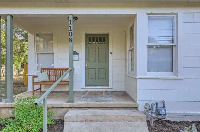 Welcome to the inviting front entry, featuring a charming porch with tasteful décor and comfortable seating. The entrance is framed by lush landscaping, offering a warm and welcoming atmosphere from the moment you arrive.