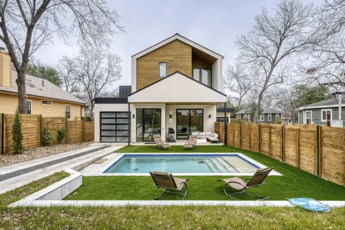 Charming exterior with a welcoming front porch, pool and beautifully landscaped yard.