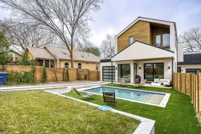 Charming exterior with a welcoming front porch, pool and beautifully landscaped yard.