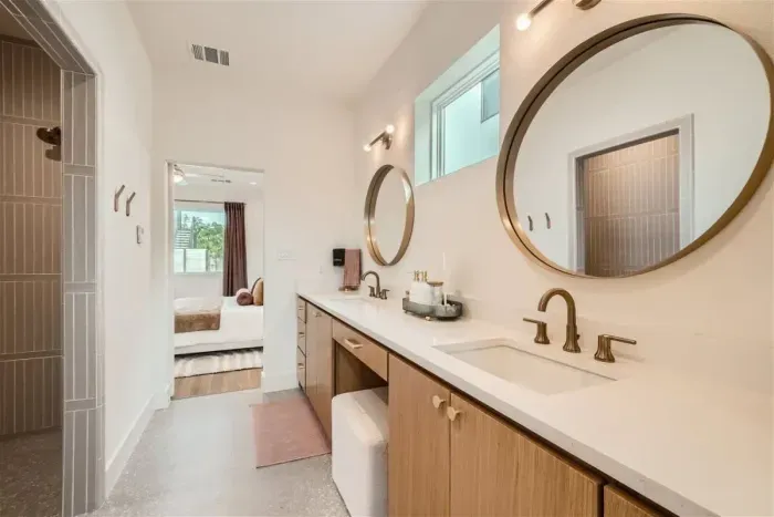 Primary bathroom with dual vanities, walk-in shower, and private restroom.