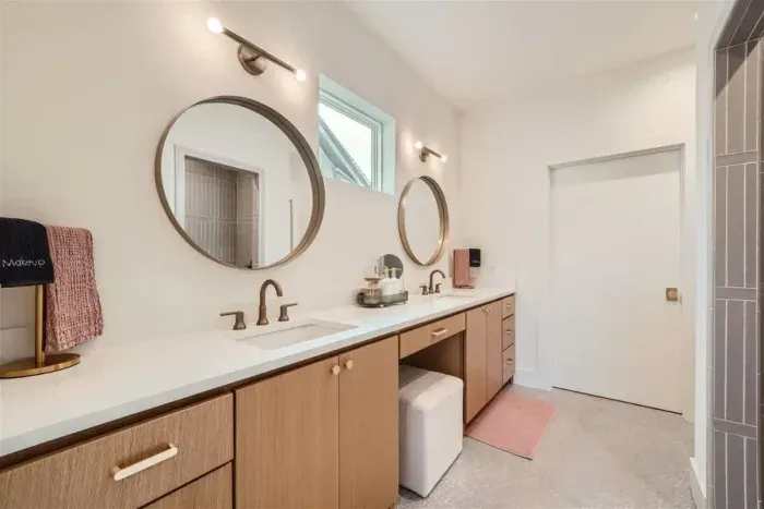 Primary bathroom with dual vanities, walk-in shower, and private restroom.