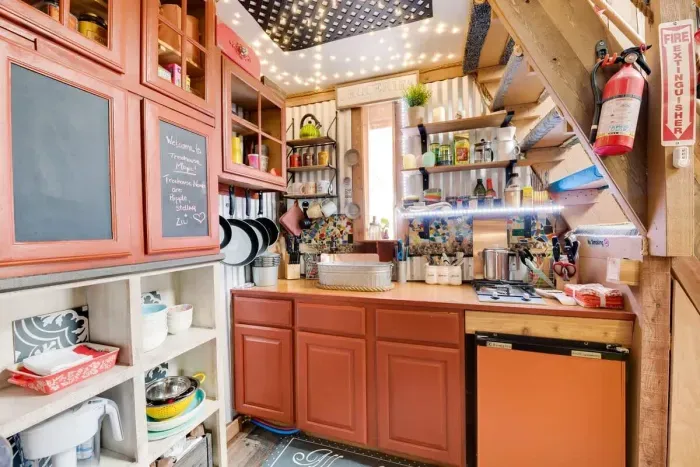 A view of the kitchen. Small fridge, propane 2-burner stove...