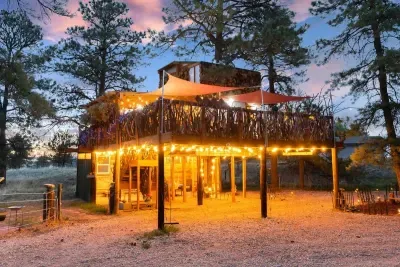 Experience treehouse magic with a charming carport lit up, creating a whimsical and cozy atmosphere. The soft glow of lights highlights the natural beauty around, offering a serene escape. Perfect for evening relaxation, this enchanting space combine