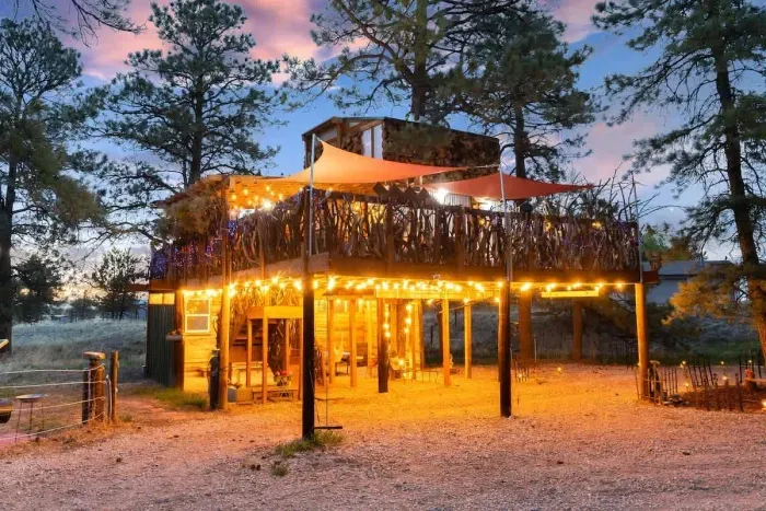 Experience treehouse magic with a charming carport lit up, creating a whimsical and cozy atmosphere. The soft glow of lights highlights the natural beauty around, offering a serene escape. Perfect for evening relaxation, this enchanting space combine