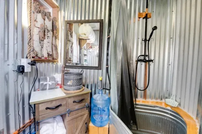 Experience a unique bathroom featuring a rustic trough tub, perfect for a relaxing soak, and a compost toilet designed for sustainability. This eco-friendly space combines comfort with mindful design, offering a practical and peaceful retreat.