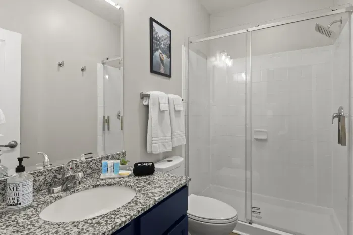 The River Room’s attached, private, full bathroom with sliding glass shower door to the with carefully selected toiletries and hotel grade towels.