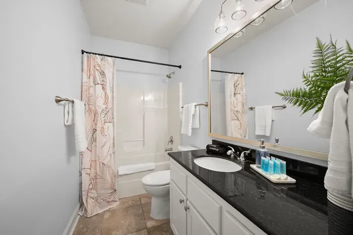 Bright and spacious bathroom featuring a large vanity, walk-in shower, and fresh, modern touches.
