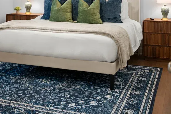 Comfortable bedding and a beautiful patterned rug add warmth and style to this inviting bedroom.