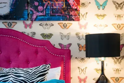 Discover whimsical tranquility in our designer home, where colorful butterflies dance amidst an inviting and restful bed