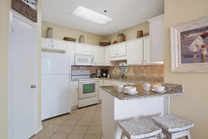 .'Kitchen with breakfast bar for two overlooking living room and dining area.