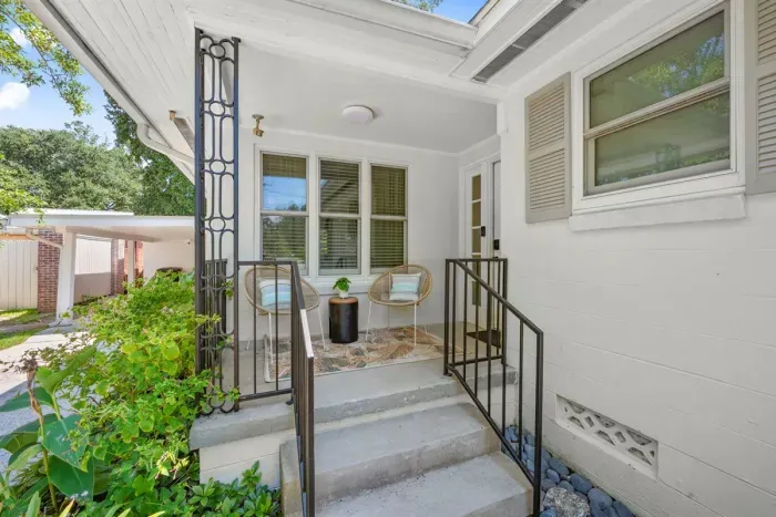 Charming Entrance: Enjoy morning coffee on the stylish patio amidst lush greenery!