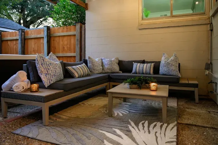 Relax and unwind in this cozy outdoor patio featuring a stylish sectional sofa, warm lighting, and a peaceful ambiance perfect for evening gatherings.