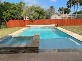 Enjoy this refreshing backyard oasis featuring a sparkling pool, attached spa, spacious stone deck, and lush fenced lawn. Perfect for sunny afternoons, family fun, and relaxing evenings in a private outdoor retreat designed for comfort and leisure.