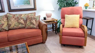 Warm, inviting living space featuring a plush sofa, tropical‑patterned accents, soft lighting, and a relaxing recliner. Thoughtful décor, natural textures, and a calm coastal vibe create a comfortable retreat for unwinding.
