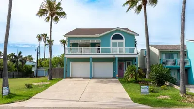 This charming three-story beach house features vibrant turquoise exterior, spacious balconies, and a private swimming pool surrounded by lounge chairs. Perfect for a relaxing getaway with stunning ocean views and ample outdoor entertainment space.