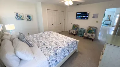 Coastal bedroom retreat features a comfy bed, plush pillows, and cheerful ocean-themed decor. Enjoy extra seating, smart TV, and convenient closet space for a relaxing stay. Perfect for unwinding in style and comfort after a day of adventure.