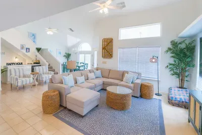 Spacious open-concept living area featuring a cozy sectional sofa, accent chairs, and a stylish wet bar. Natural light pours in from stunning arched windows, creating an inviting space perfect for socializing and family gatherings.