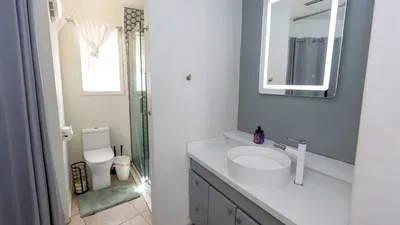 Bright, modern bathroom featuring a sleek vanity, illuminated mirror, walk‑in shower, and clean finishes throughout. Thoughtfully designed for comfort, this refreshed space adds a polished, spa‑like touch to your coastal getaway.