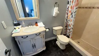 Charming Floral Full Bathroom
Elegant white vanity, pedestal sink & walk-in shower w/ vibrant floral curtain! Stocked amenities, fresh towels, soft lighting. Spotless & stylish for relaxing post-beach showers.