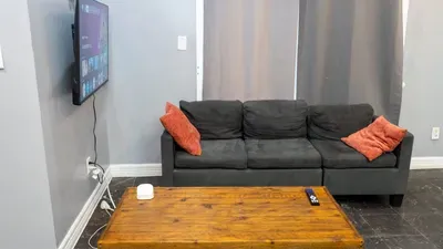 Relaxing Gray Sofa & TV Lounge
Inviting charcoal sofa w/ burnt orange pillows & large wall TV for movie nights! Rustic wood table, smart controls—cozy nook to unwind in style after sunny Galveston days.