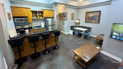 Spacious Eat-In Kitchen & Dinette
Modern kitchen boasts wood cabinets, SS fridge, microwave & sleek black bar stools! Cozy dinette table for 4, wall TV, artful decor. Perfect for family breakfasts & gatherings!