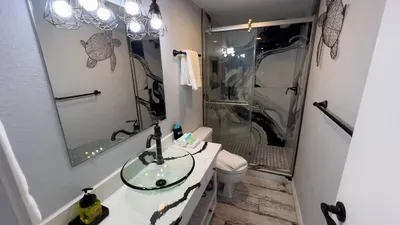 Freshen up in a designer bathroom with a show-stopping glass vessel sink, striking black-and-white marble shower, and bold lighting. Nautical accents and plush towels complete this stylish, comfortable space for your beachside getaway.