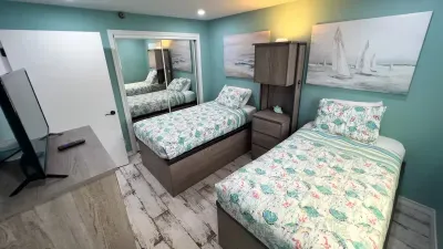 Kids and guests will love this cheerful bedroom with twin beds, playful sea turtle bedding, custom storage, and calming blue walls. Ocean-inspired art and mirrored closets create a welcoming, airy feel—perfect for rest after a day at the beach.