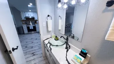 Pamper yourself in a modern bathroom featuring a sleek vessel sink, marble-style vanity, and stylish lighting. Enjoy thoughtful amenities and spa-like touches, creating a refreshing, relaxing space just steps from the kitchen and living area.