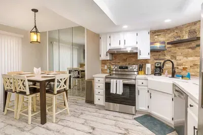 Enjoy cooking and dining in style with a modern kitchen featuring stainless appliances, farmhouse sink, and a chic stone backsplash. Gather at the spacious dining table for memorable meals in a bright, open layout with coastal touches throughout.