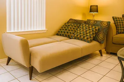 Spacious Convertible Sofa in Cozy Living Room – Ideal for Relaxing or Sleeping, with Stylish Decor, Natural Light, and Functional Layout