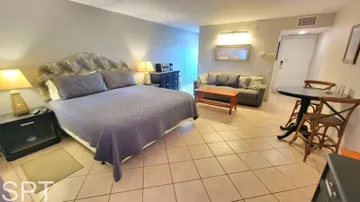 Inviting guest suite featuring a plush bed, comfy seating area, dining nook, and convenient in‑room amenities including a microwave and coffee station. Warm lighting and thoughtful design create a relaxing, comfortable stay for every guest.