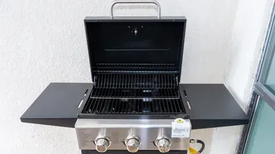 Premium Propane Grill Station on Sunny Patio. Fire up this sleek 3-burner stainless steel BBQ with ample prep shelves on a sturdy black countertop—ideal for sizzle sessions, family feasts, and sunset grilling.